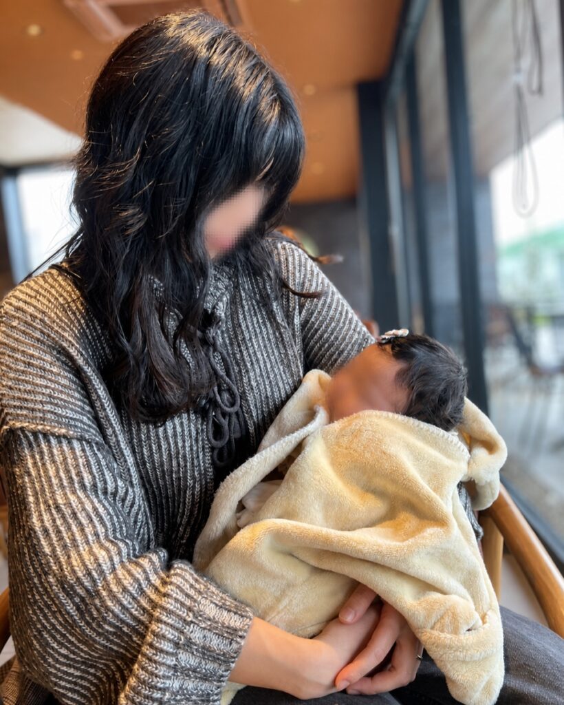 mocmofのお星様おくるみに包まれた赤ちゃんを外出先で抱っこしている様子