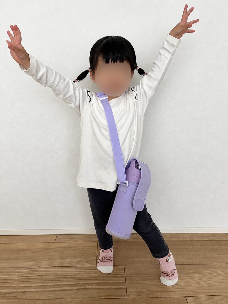 水筒をショルダーストラップに入れて喜ぶ２歳児